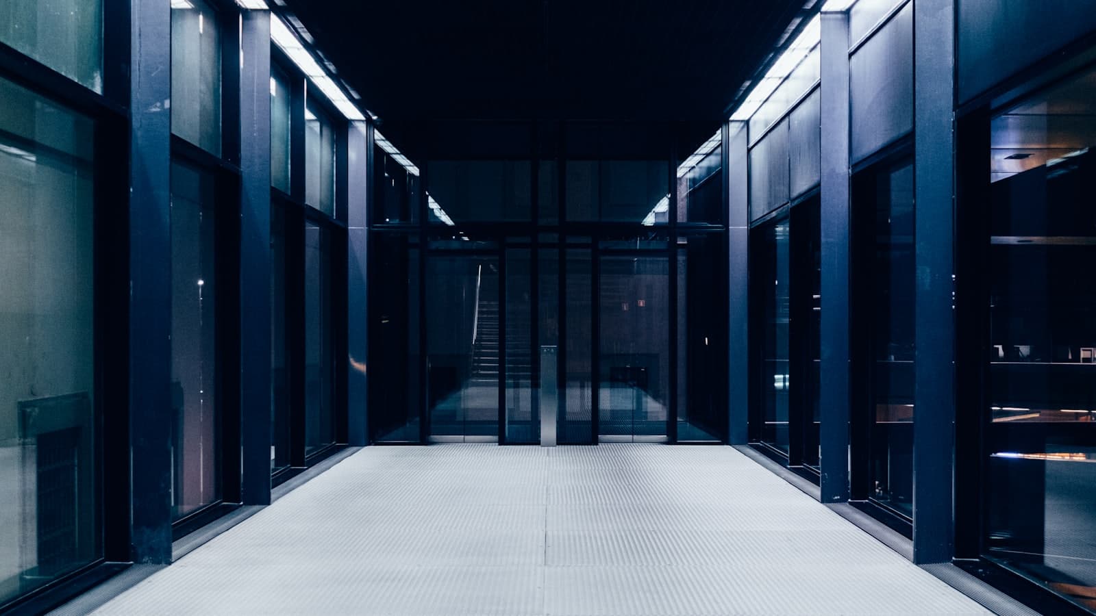 A dark corridor inside a data facility with glass-front cabinets on either side